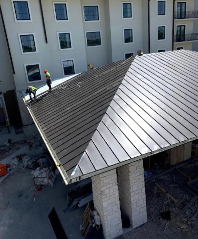 Crew installing standing seam metal roof panels on a commercial project in Susanville